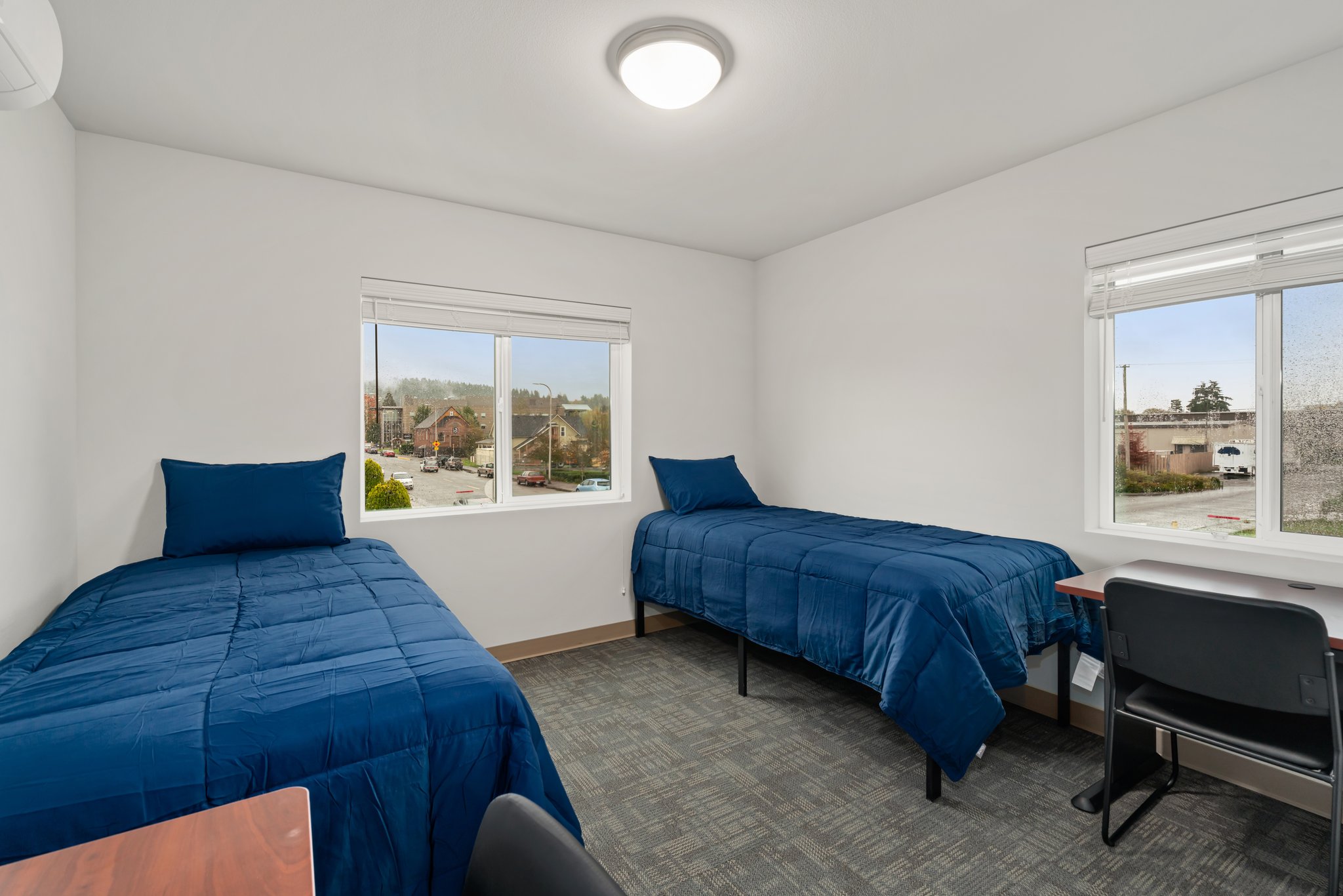 Closer view of beds, desks, and windows in a typical bedroom.