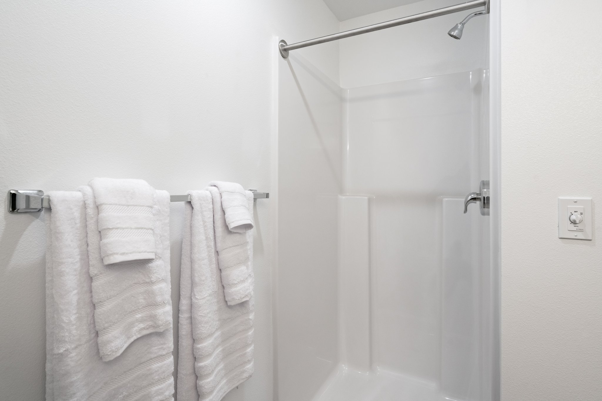 Closeup of bathroom shower and towel rack with towels.