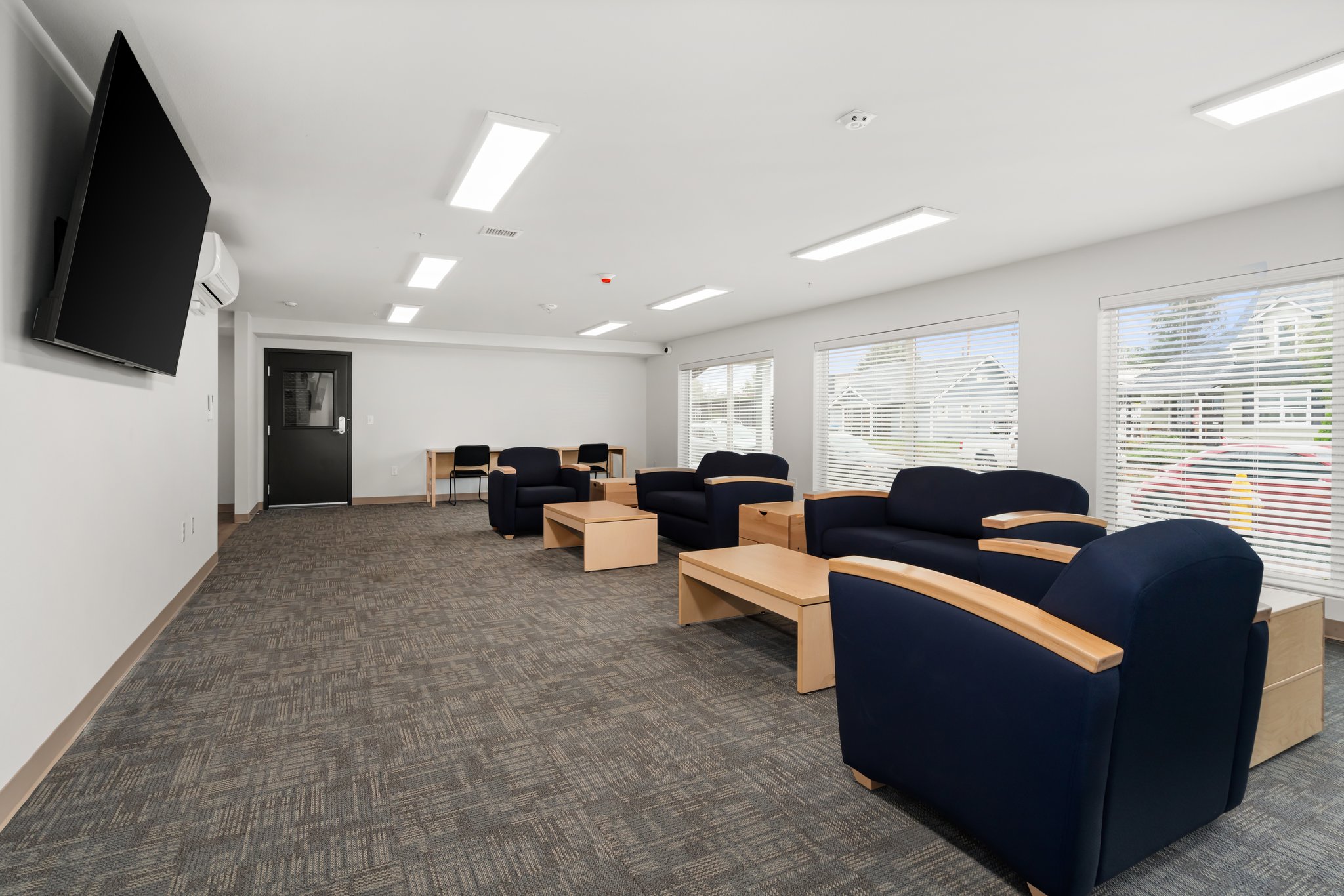 Long view of community room showing TV, chairs, and windows.