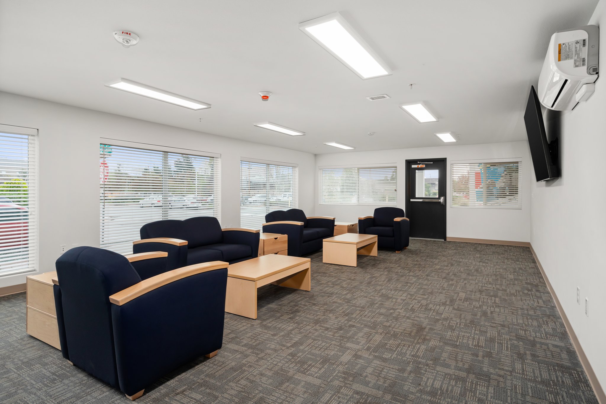 Community room looking toward windows and comfortable chairs.