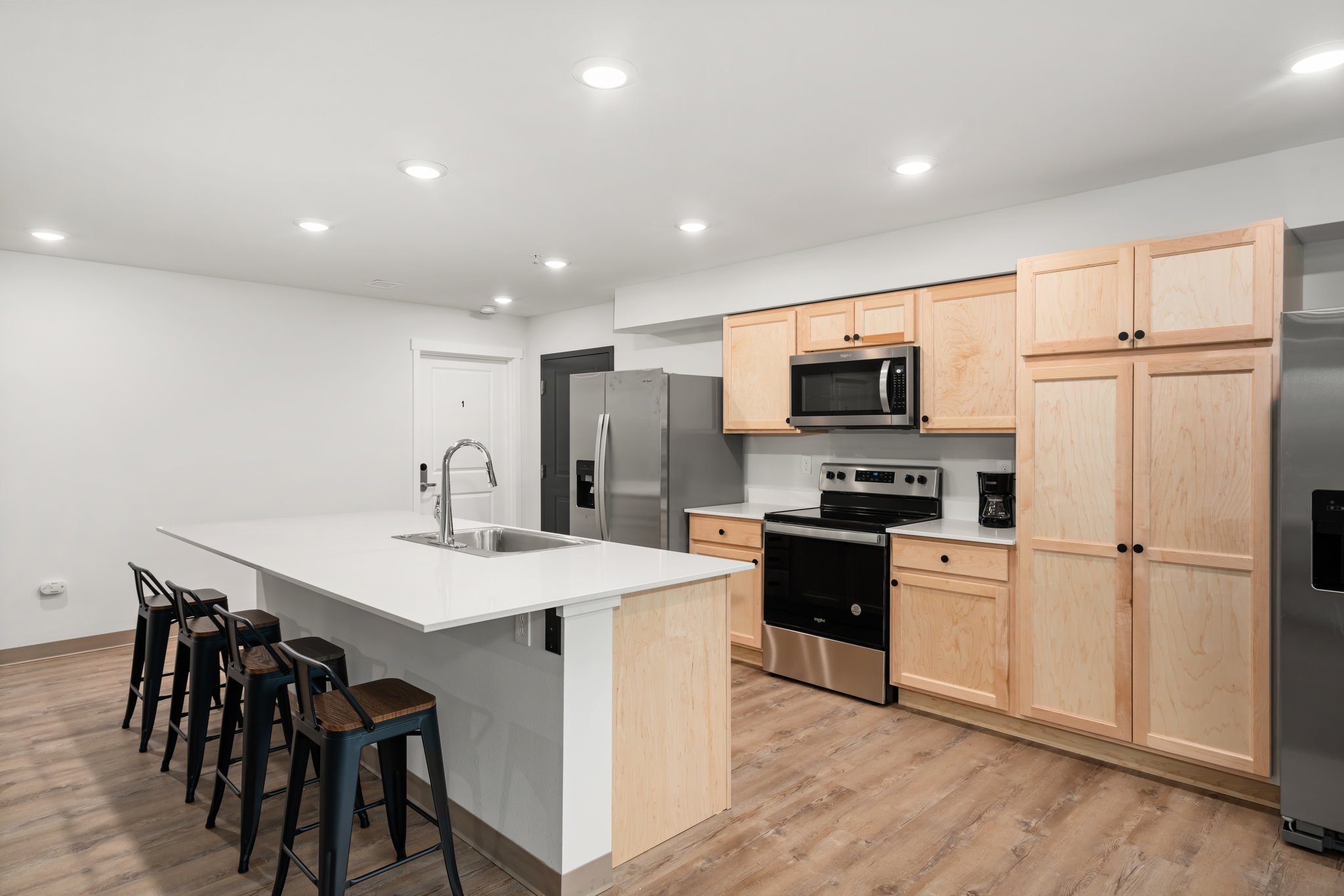 Second view of kitchen showing island with barstools.